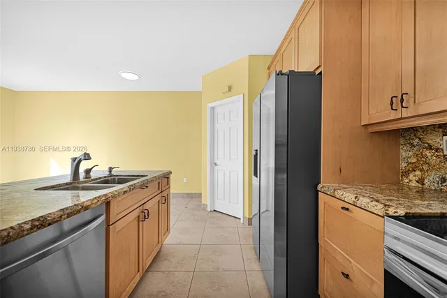 a kitchen with stainless steel appliances granite countertop a sink and a refrigerator