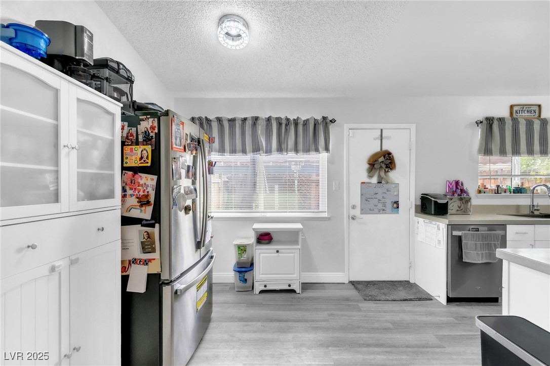 111 Maple Street Henderson, NV 89015 - Photo 16 of 37 Kitchen with stainless steel appliances, white cabinets, light countertops, glass insert cabinets, and a textured ceiling