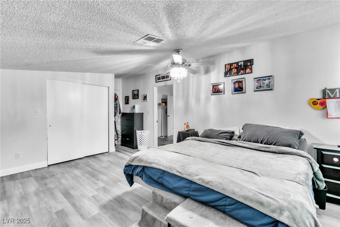 111 Maple Street Henderson, NV 89015 - Photo 23 of 37 Bedroom with light wood-type flooring, a textured ceiling, a ceiling fan, and a closet