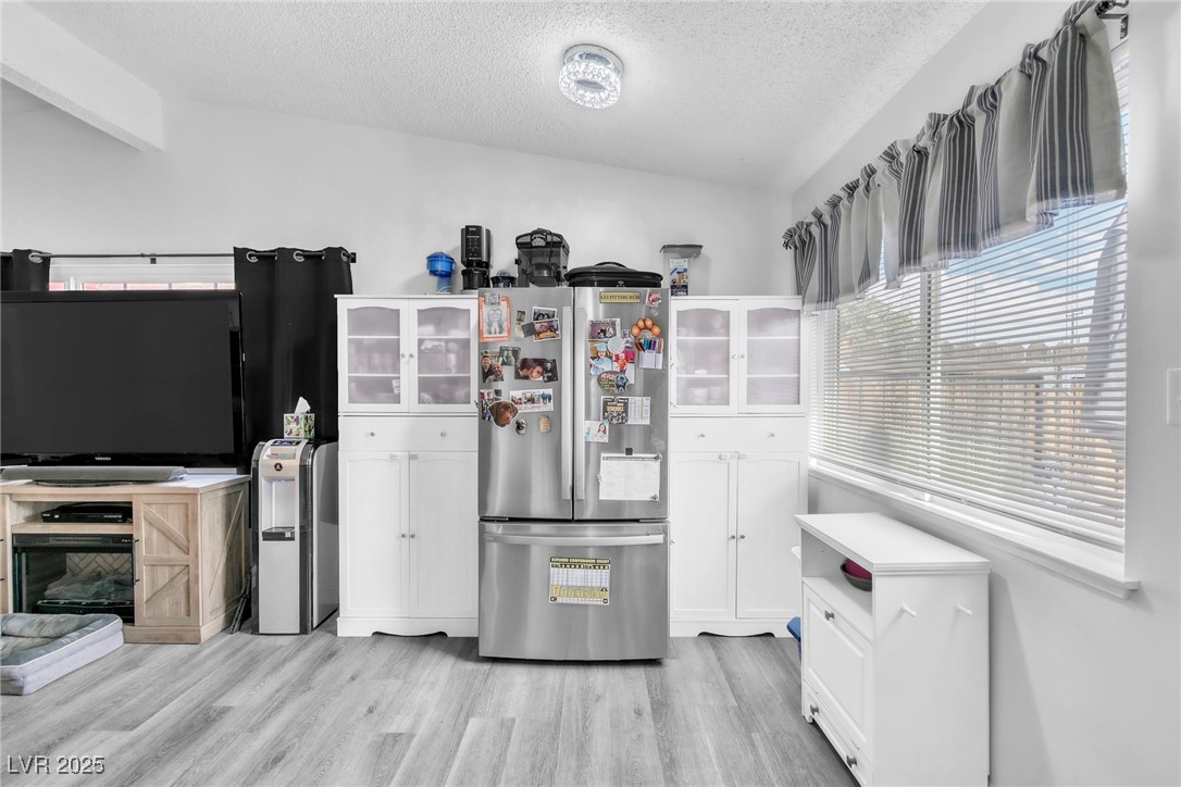 111 Maple Street Henderson, NV 89015 - Photo 3 of 37 Kitchen featuring freestanding refrigerator, glass insert cabinets, white cabinets, light wood-style floors, and a textured ceiling
