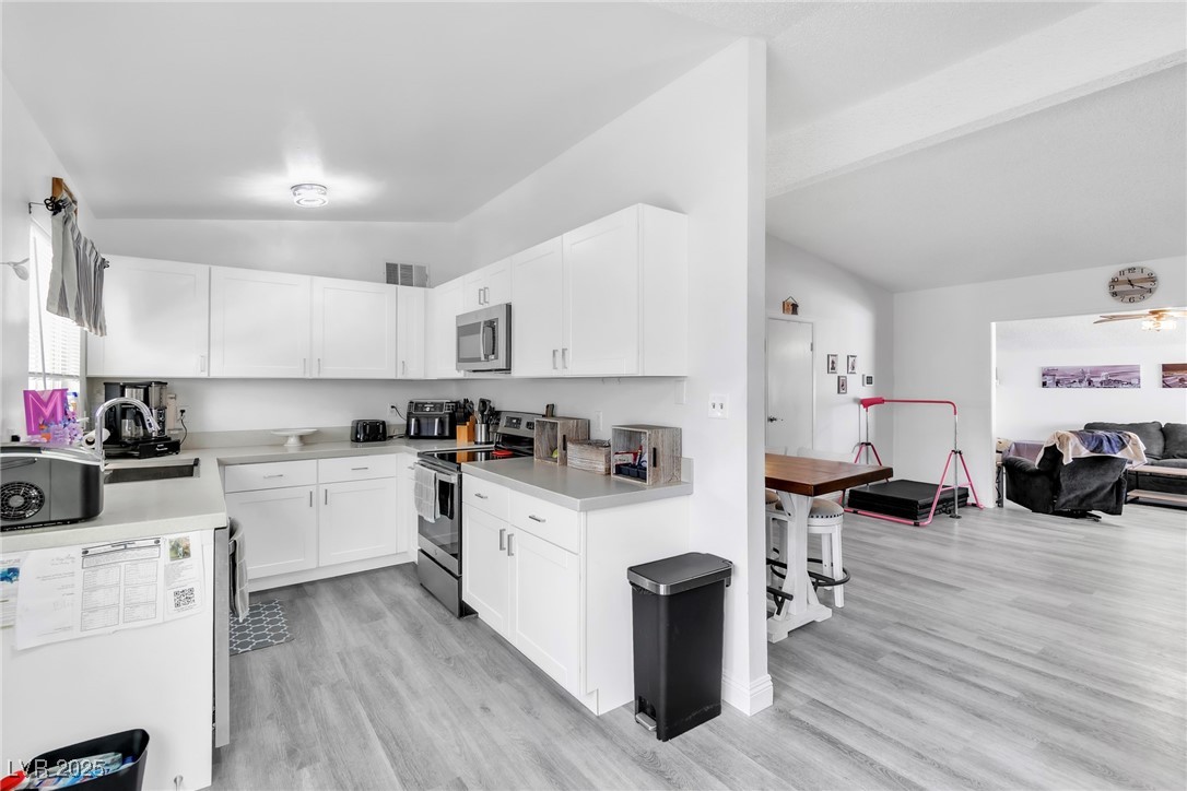 111 Maple Street Henderson, NV 89015 - Photo 37 of 37 Kitchen featuring lofted ceiling, light countertops, open floor plan, light wood-style floors, and stainless steel appliances