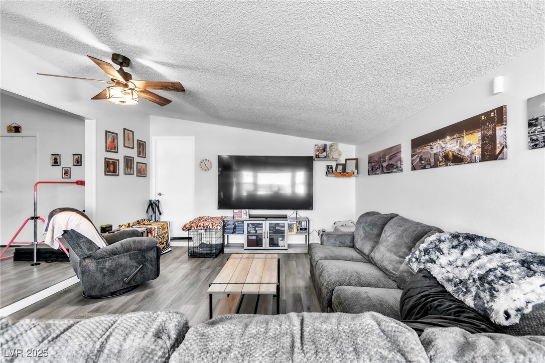 111 Maple Street Henderson, NV 89015 - Photo 8 of 37 Living area featuring vaulted ceiling, a textured ceiling, wood finished floors, and ceiling fan