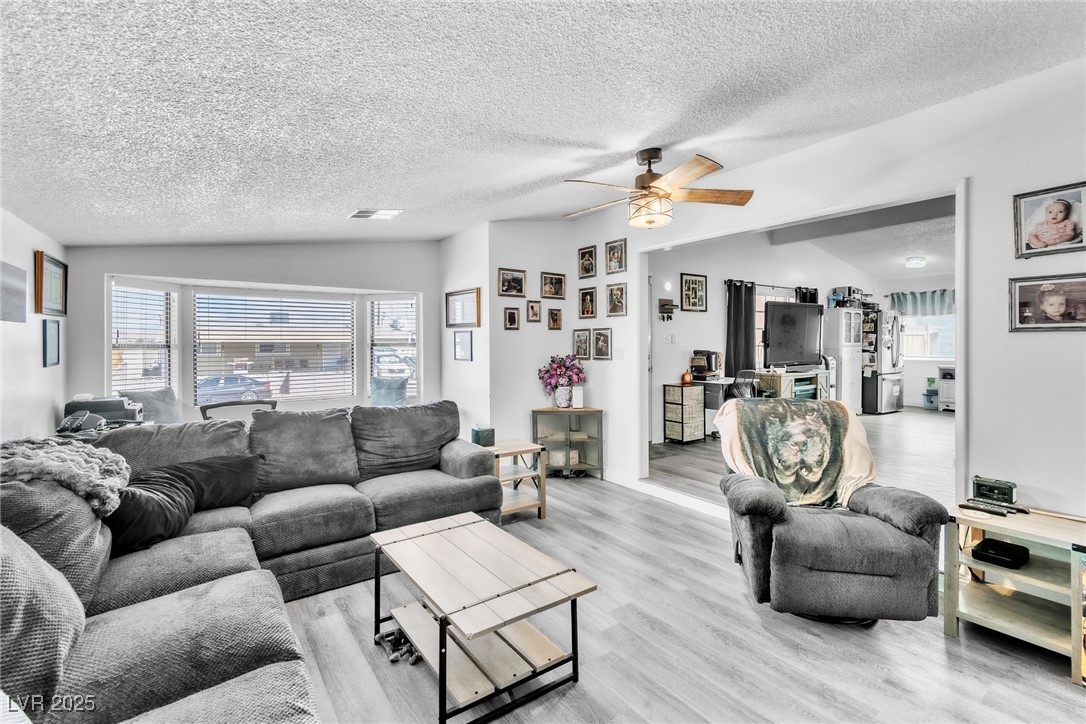 111 Maple Street Henderson, NV 89015 - Photo 9 of 37 Living area with vaulted ceiling, a textured ceiling, ceiling fan, and wood finished floors