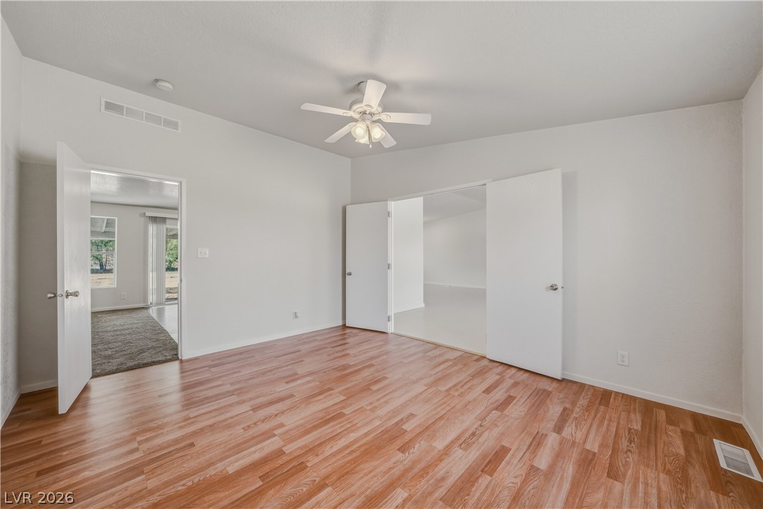 1890 West Dyer Road Pahrump, NV 89048 - Photo 29 of 40 This airy bedroom features sleek wood flooring and a modern ceiling fan, offering comfort and style.