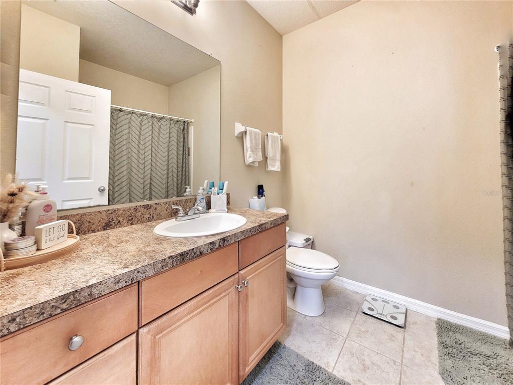 1185 Southwest 9th Road, Unit 306 Gainesville, FL 32601 - Photo 22 of 30 a bathroom with a granite countertop sink a toilet and a mirror