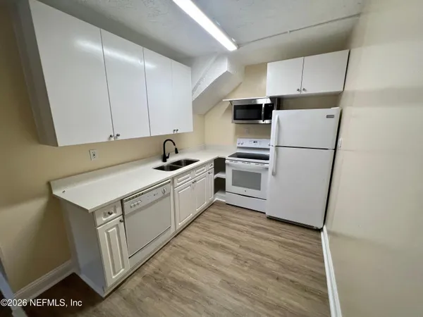 a kitchen with white cabinets and white appliances