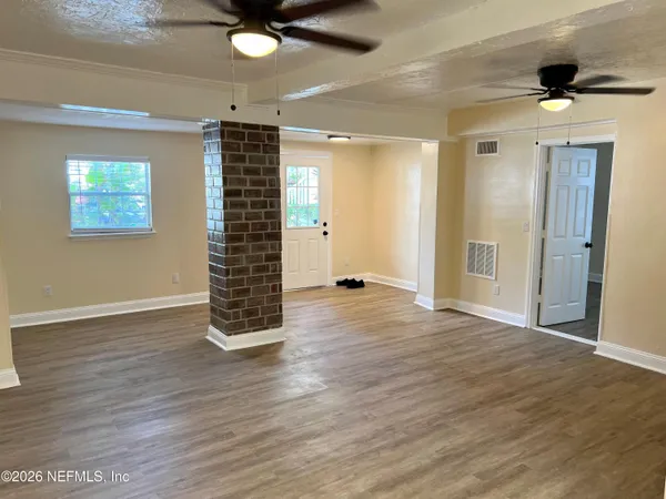 a view of an empty room with wooden floor and a window