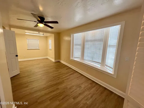 a view of an empty room with wooden floor and a window