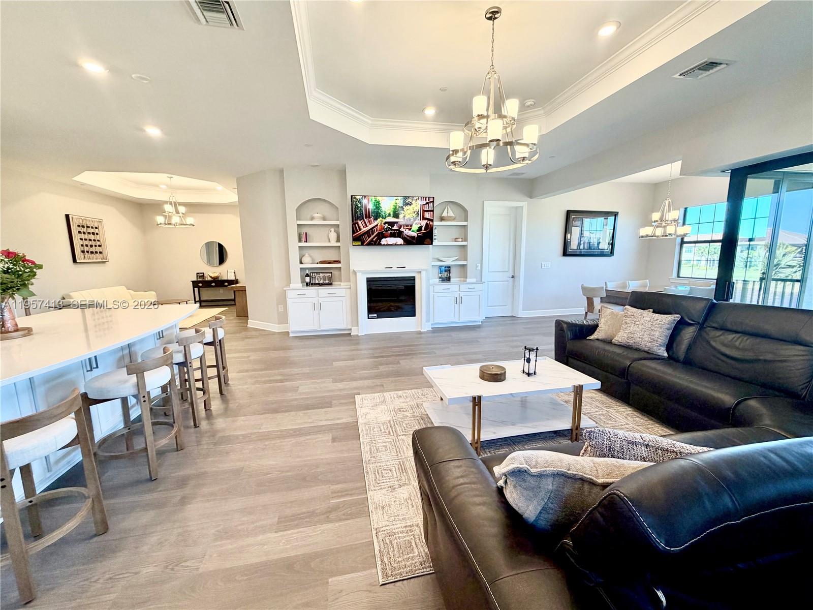 15323 Lucerna Street, Unit 204 Naples, FL 34114 - Photo 13 of 29 a living room with furniture a chandelier and a flat screen tv