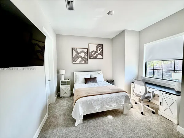 a bedroom with a bed and a flat tv screen on the dresser
