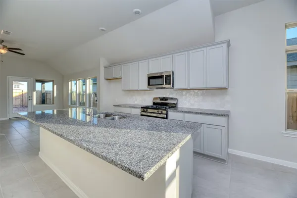 a kitchen with granite countertop a sink a counter top space appliances and cabinets