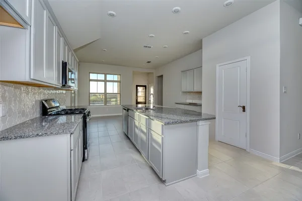 a large kitchen with granite countertop a sink and cabinets