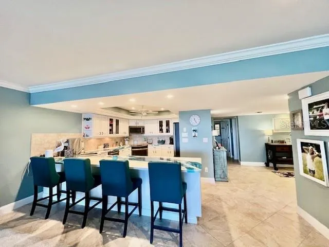a dining hall with stainless steel appliances a dining table and chairs with the kitchen view