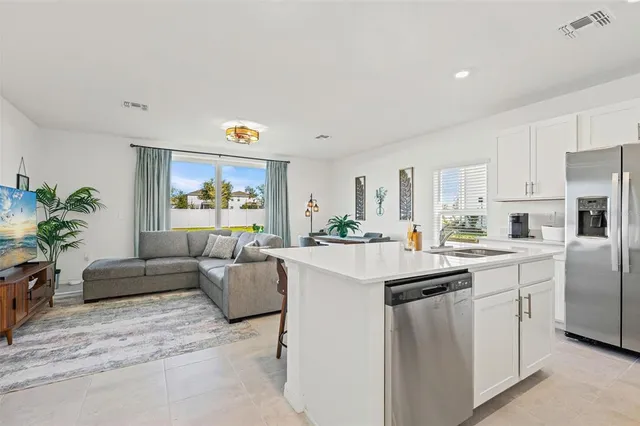 a living room with stainless steel appliances furniture and a potted plant