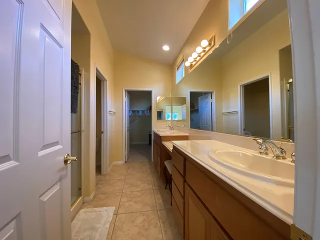 a spacious bathroom with a granite countertop sink a mirror and a shower