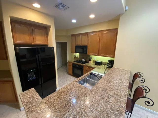a kitchen with granite countertop a refrigerator and a sink