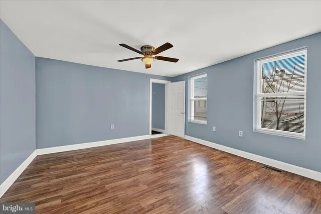 a view of an empty room with a window and wooden floor