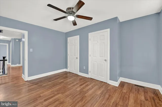 an empty room with wooden floor and a ceiling fan