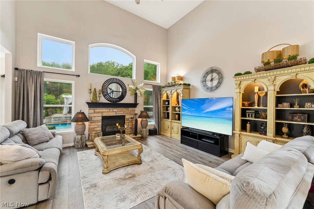 8874 Sharp Road Olmsted Falls, OH 44138 - Photo 6 of 42 Soaring ceilings define this living space, featuring a stone-clad fireplace with a dark mantel, large windows including an arched accent window.