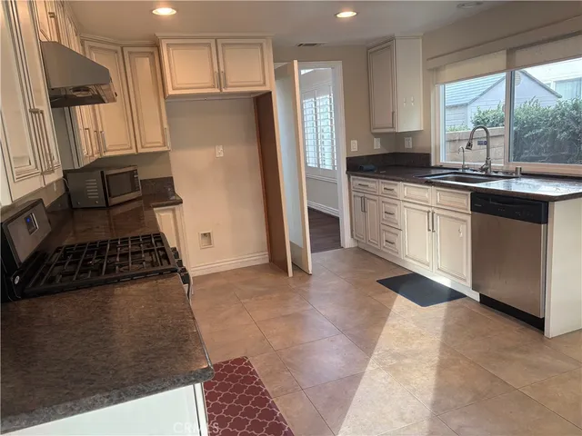 a kitchen with granite countertop a refrigerator stove top oven and sink