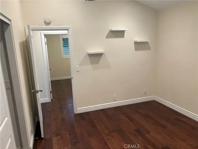 an empty room with wooden floor and entrance