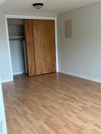 a view of an empty room with wooden floor and closet