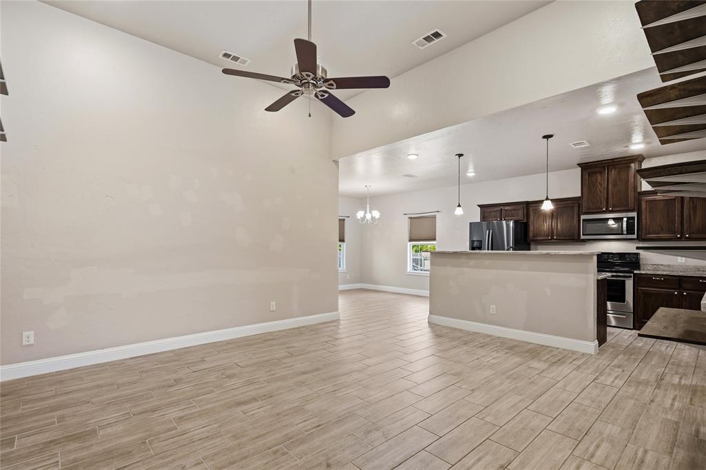 1502 Reed Street Greenville, TX 75401 - Photo 8 of 26 Open-concept living area featuring wood-finish tile flooring, vaulted ceilings, and a ceiling fan