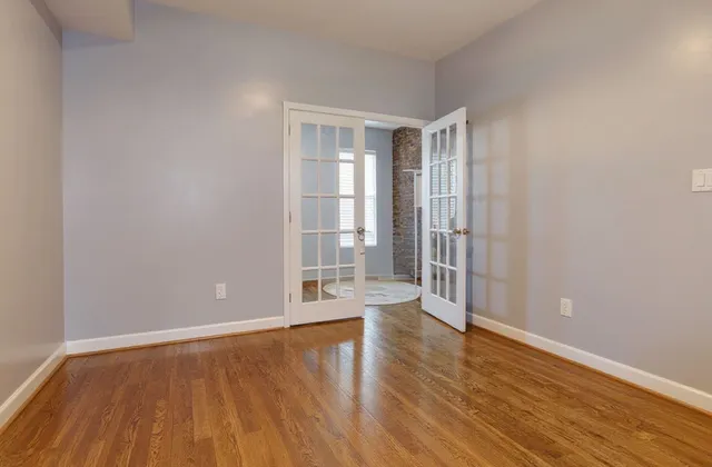 a view of an empty room with wooden floor and a window