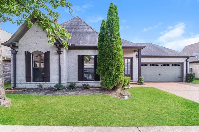 a front view of a house with a garden and yard