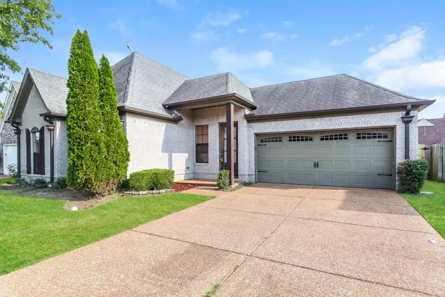 front view of a house with a yard and an trees