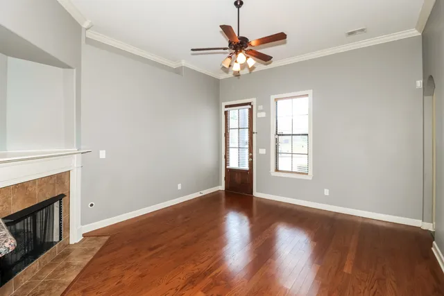 an empty room with wooden floor fan and windows