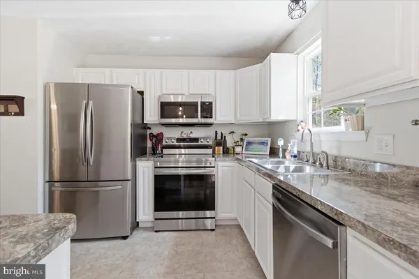 a kitchen with stainless steel appliances granite countertop a refrigerator stove microwave and sink