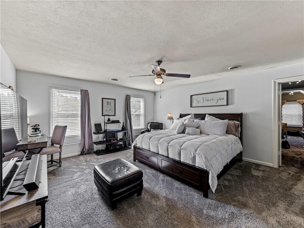 215 Pineywood Road Griffin, GA 30224 - Photo 34 of 49 a spacious bedroom with a bed a couch and a chandelier