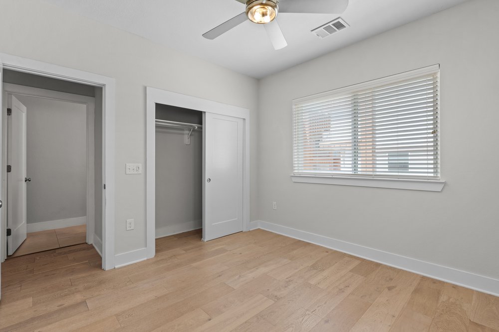 2827 Manor Road, Unit 2201 Austin, TX 78722 - Photo 20 of 40 Bedroom featuring wood-finish flooring, a ceiling fan with integrated lighting, a window with horizontal blinds, and a closet with sliding doors