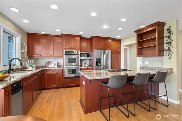 a kitchen with stainless steel appliances granite countertop a stove top oven a sink dishwasher and cabinets with wooden floor