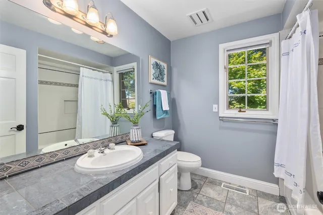 a bathroom with a granite countertop double vanity sink a mirror and a toilet