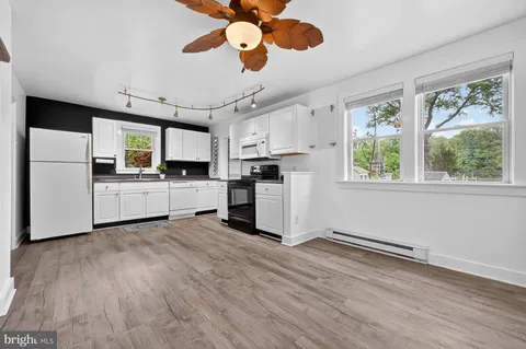a kitchen with stainless steel appliances kitchen island wooden floors and white cabinets