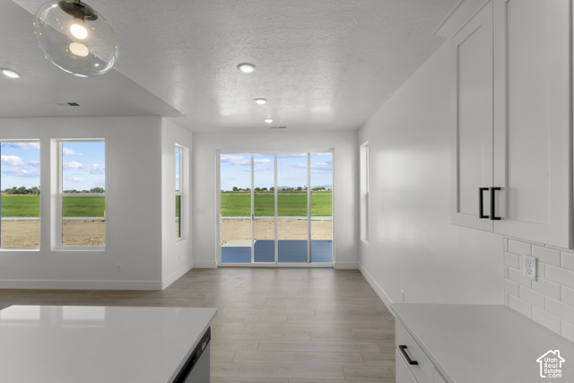 205 East 690th Street North Logan, UT 84321 - Photo 31 of 52 Recessed lighting, wood-finish flooring, white cabinetry with dark hardware, subway tile backsplash, and sliding glass doors