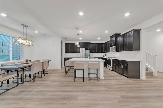 a kitchen with stainless steel appliances kitchen island granite countertop a table chairs sink and cabinets