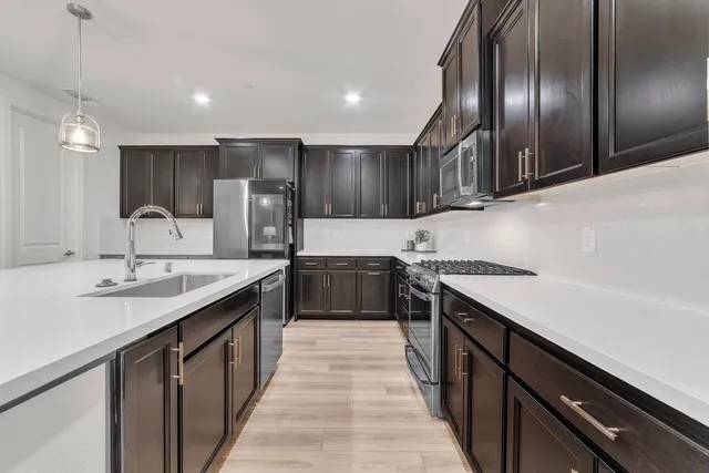 a kitchen with stainless steel appliances granite countertop sink stove and refrigerator
