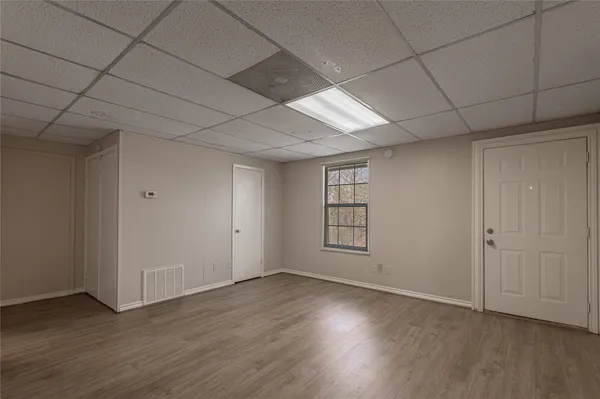 a view of an empty room with window and wooden floor