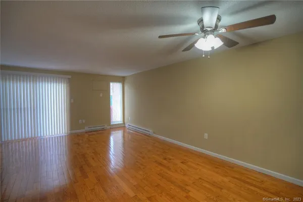 an empty room with wooden floor and chandelier fan
