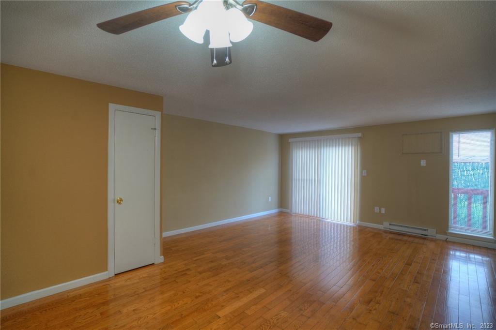 528 Shennecossett Road, Unit 14 Groton, CT 06340 - Photo 5 of 18 an empty room with wooden floor chandelier fan and windows