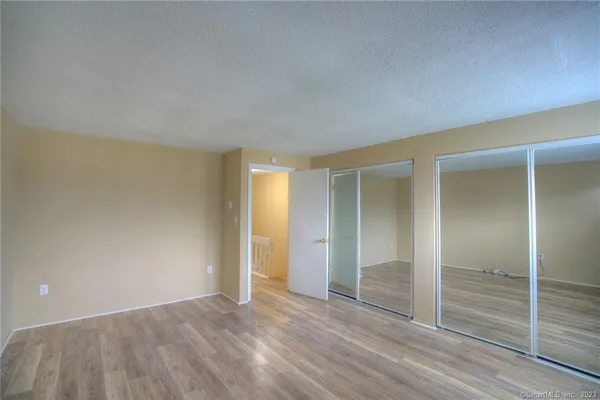 an empty room with wooden floor & closet area