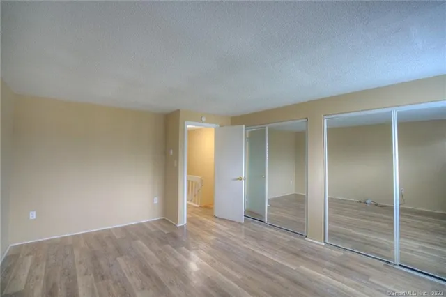 an empty room with wooden floor & closet area