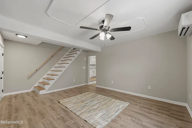 an empty room with wooden floor staircase and ceiling fan