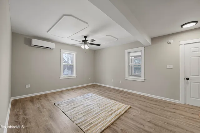 a view of an empty room with a window and wooden floor