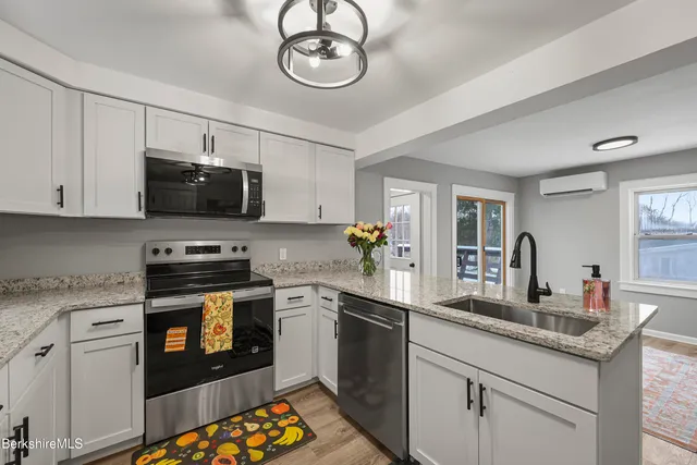 a kitchen with stainless steel appliances granite countertop a sink dishwasher stove top oven and cabinets with wooden floor