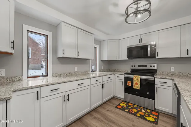 a kitchen with granite countertop a stove a sink and a microwave