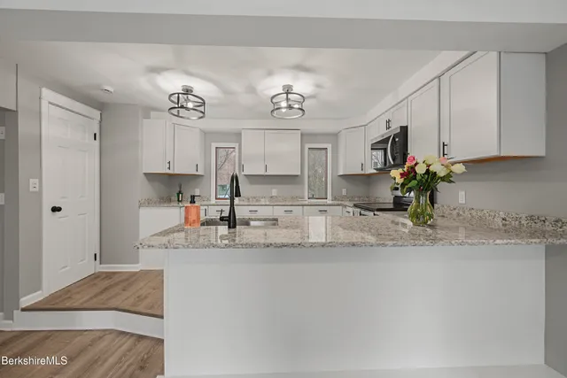 a view of a kitchen with kitchen island a sink wooden floor and counter top space